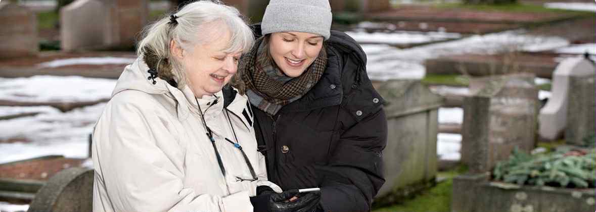 To damer ser på en QR brikke på gravstein